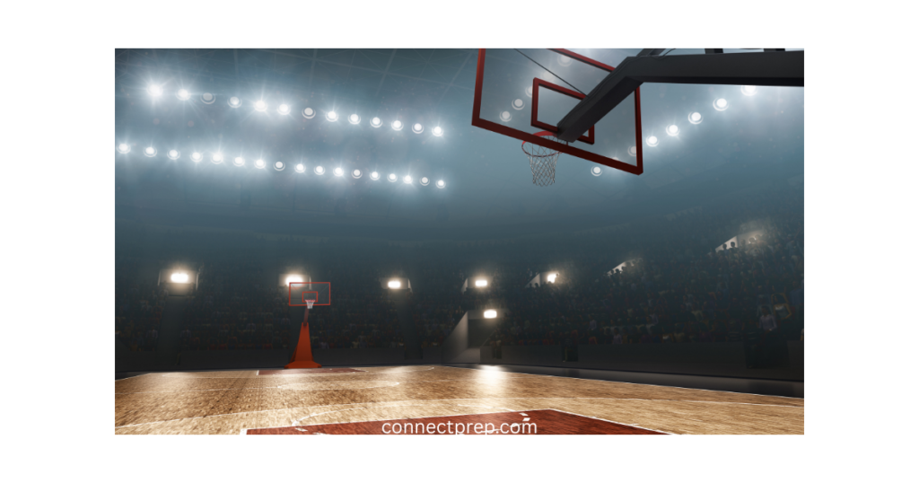 An empty indoor basketball court under bright stadium lights, showing two basketball hoops and a wooden floor, with a large audience seated in the background. The text connectpreo.com is visible at the bottom.